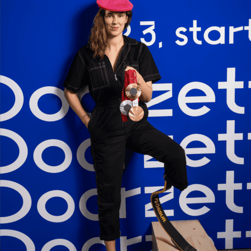 Kimberly Alkemade in zwart pak met roze baret, met haar paralympische medailles en haar Össur sprintblade